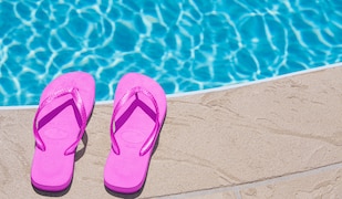 pinkes Paar Flip Flops an einem Pool